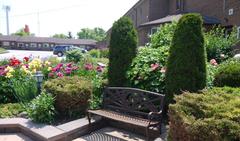Newmarket Inn | East Gwillimbury, Ontario, L9N 0J2 | Brown bench in outdoor garden surrounded by various plants